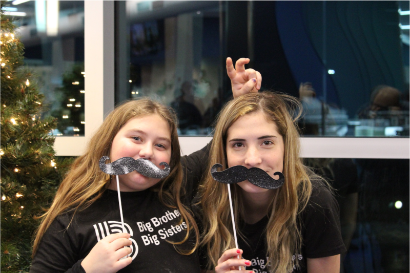 2 girls holding mustache masks to their faces