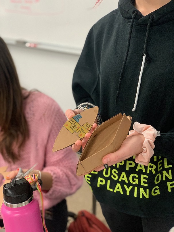 student holding cardboard boat