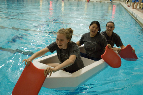 college students paddling cardboard boats