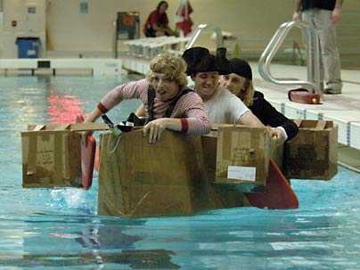 college students paddling cardboard boats