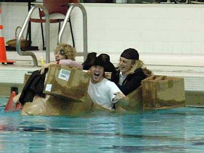 college students paddling cardboard boats