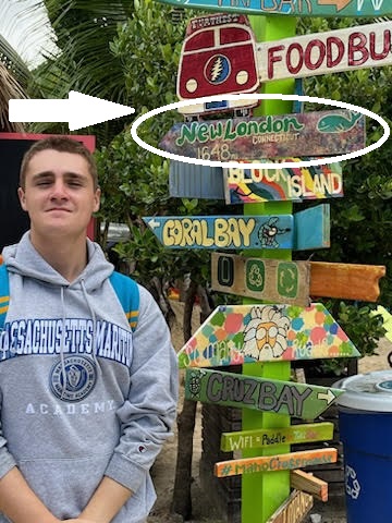 cadet standing next to sign on beach