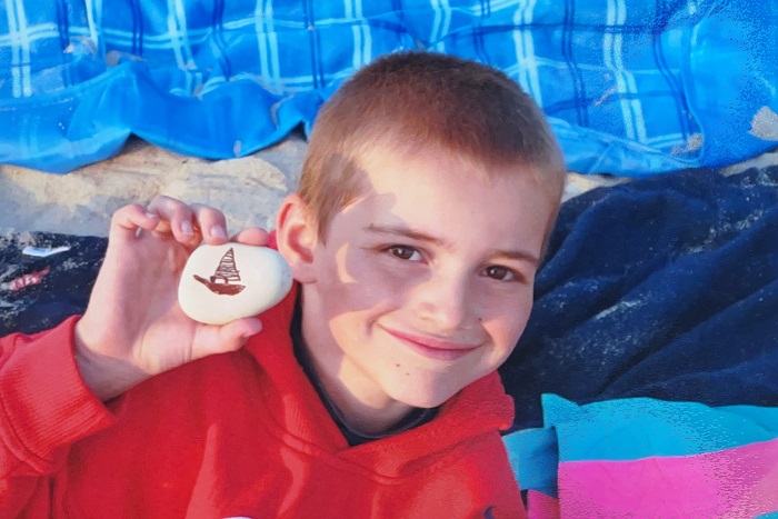 Liam holding a rock with a sailboat on it