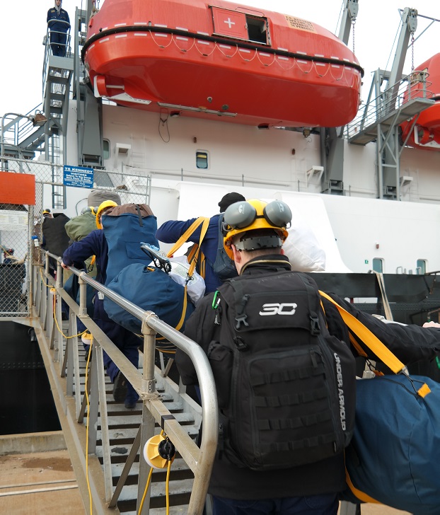 cadets carry sea bags onto ship