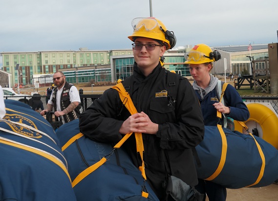 cadets carry sea bags onto ship