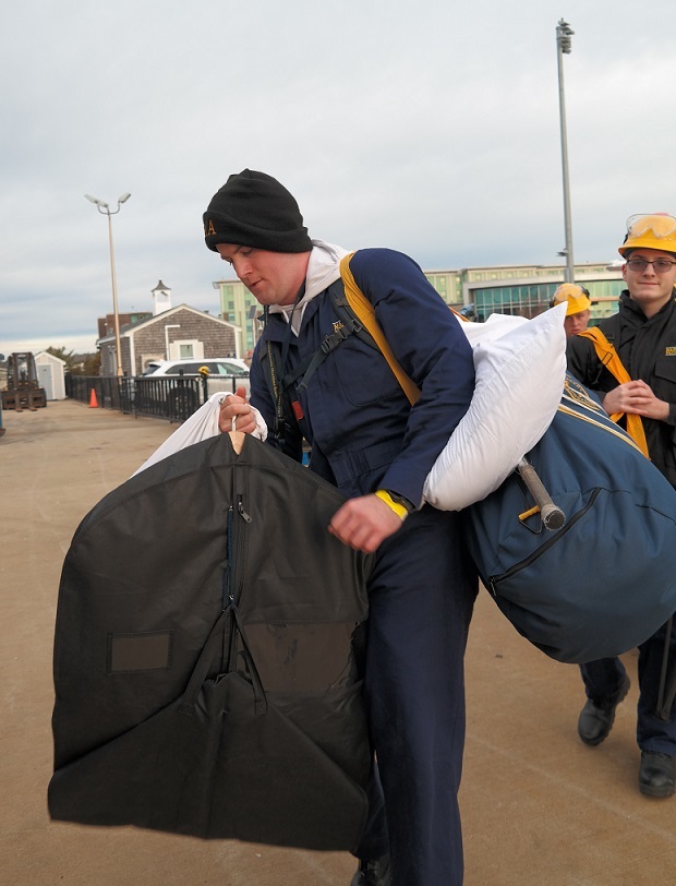 cadets carry sea bags onto ship