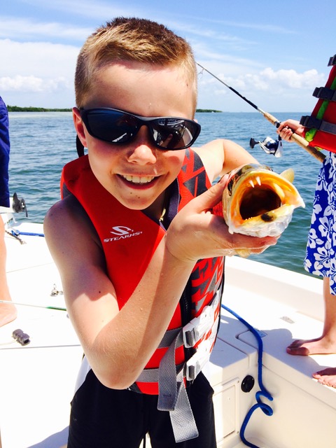 young Kolten holding a fish with an open mouth