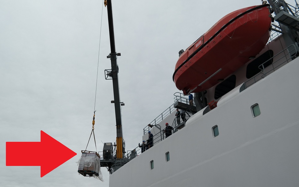 crane lifting pallets to ship