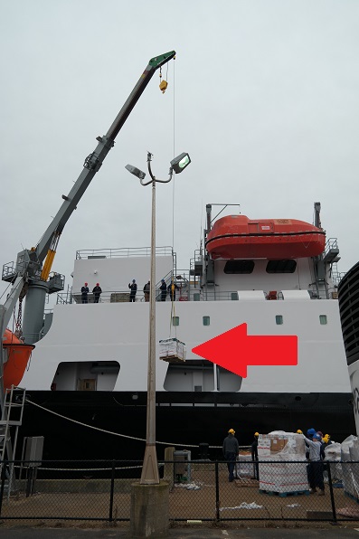 crane lifting pallets to ship