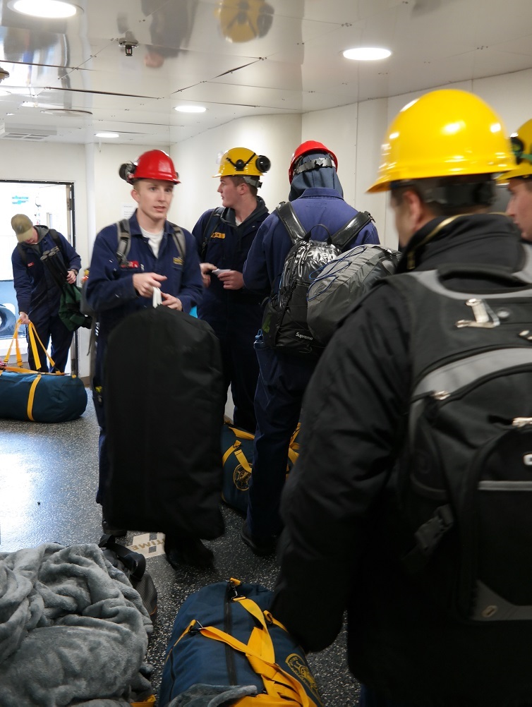 cadets carry sea bags onto ship