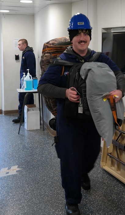cadets carry sea bags onto ship