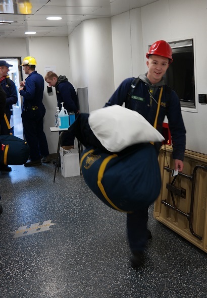 cadets carry sea bags onto ship