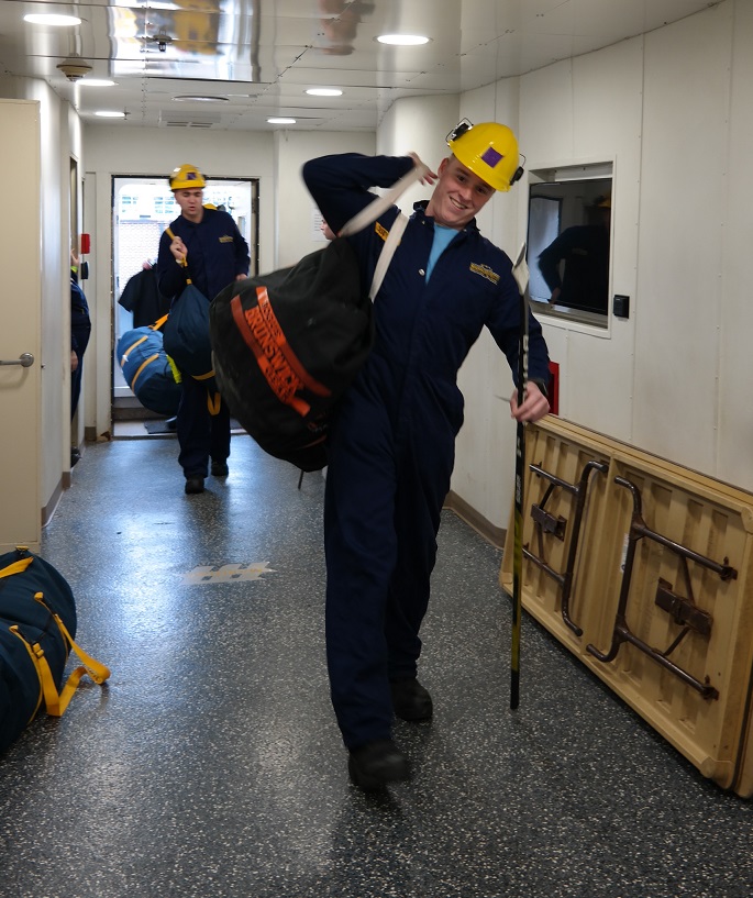 cadets carry sea bags onto ship