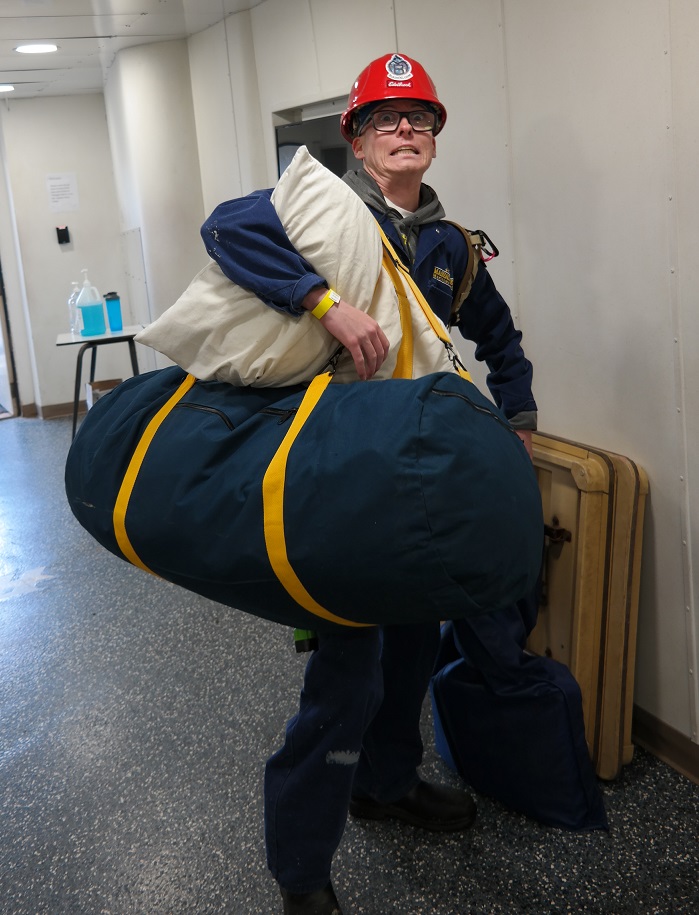 cadets carry sea bags onto ship