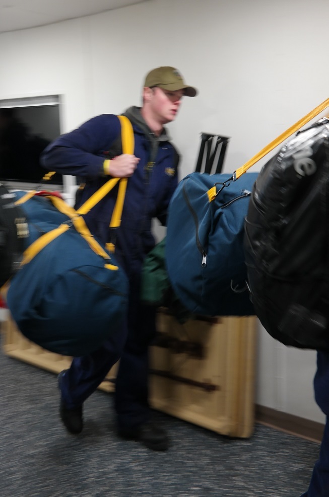 cadets carry sea bags onto ship