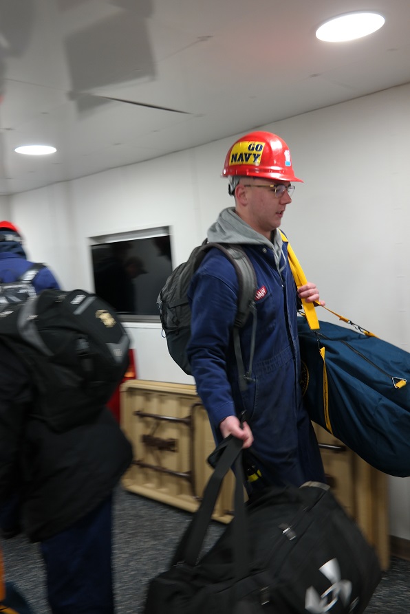 cadets carry sea bags onto ship