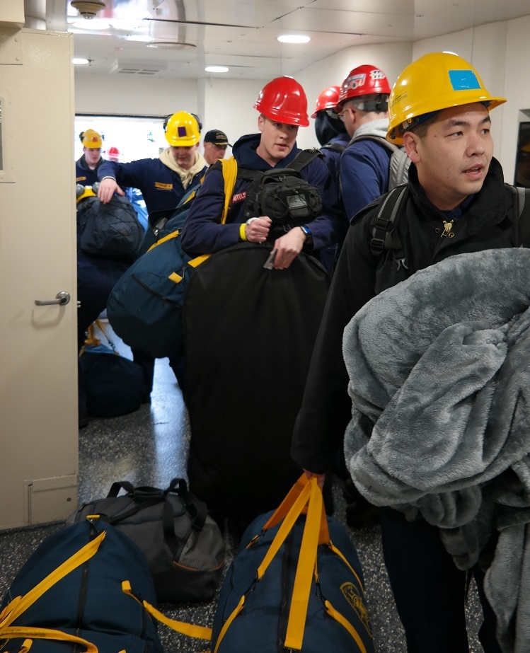 cadets carry sea bags onto ship