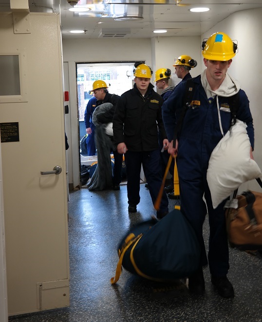 cadets carry sea bags onto ship
