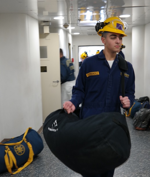 cadets carry sea bags onto ship