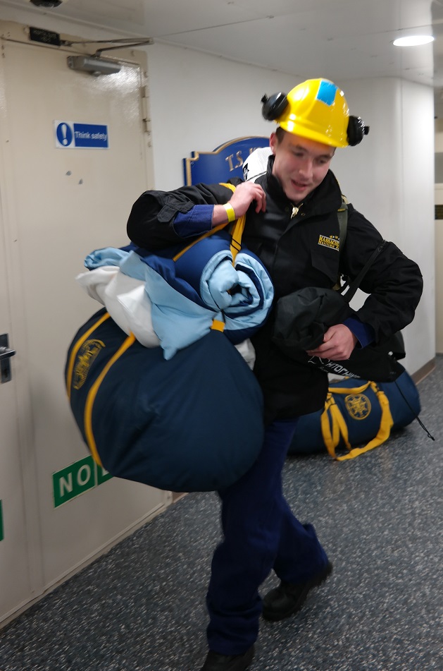 cadets carry sea bags onto ship