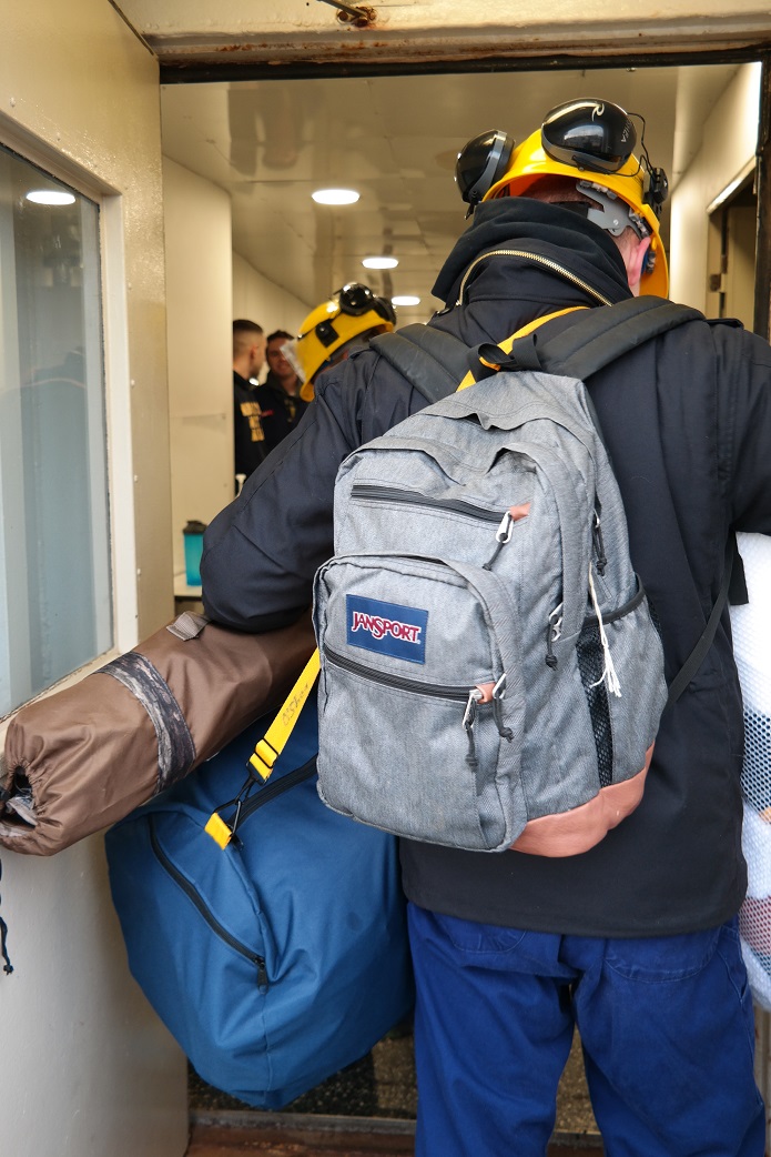 cadets carry sea bags onto ship