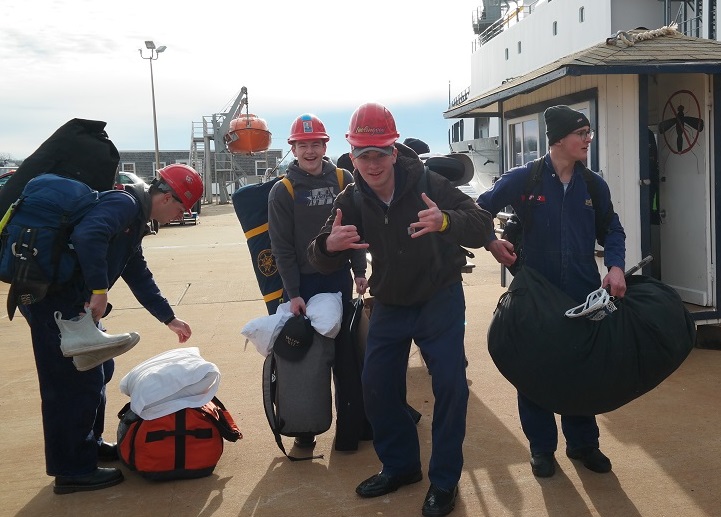 cadets carry sea bags onto ship