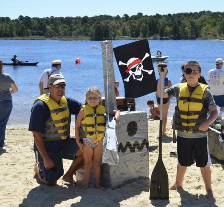 Sam, dad, and sister with cardboard pirate ship