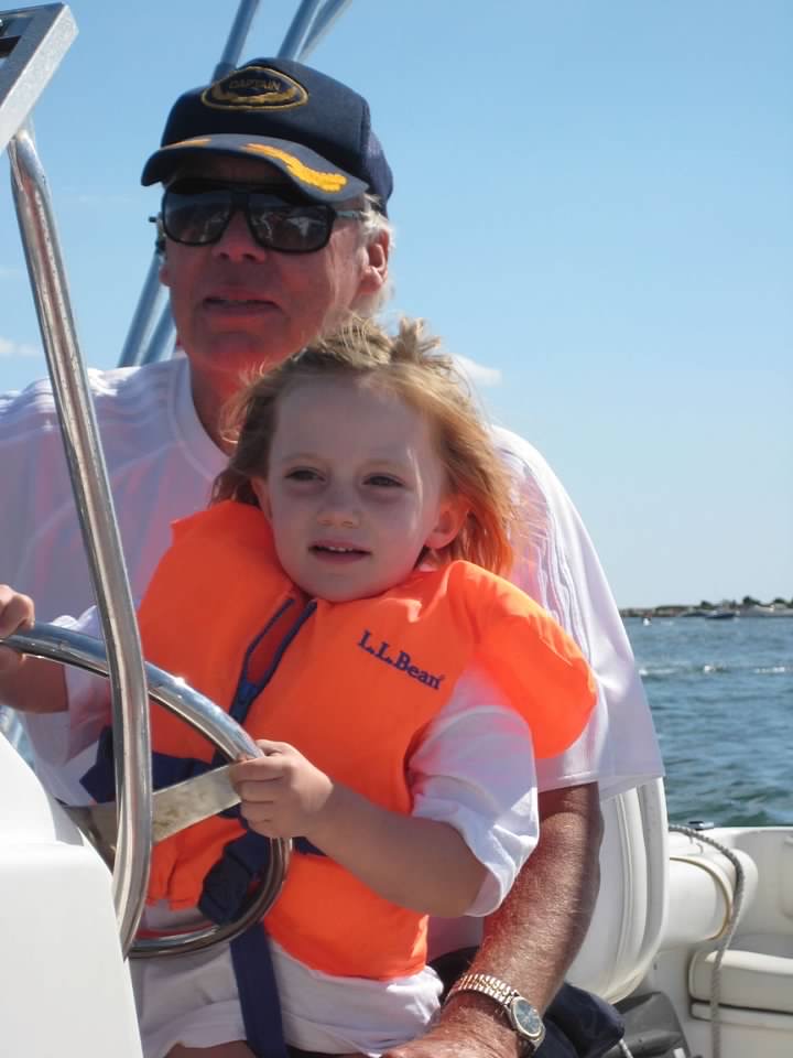 Sydney is with her grandfather in a boat, wearing a lifejacket
