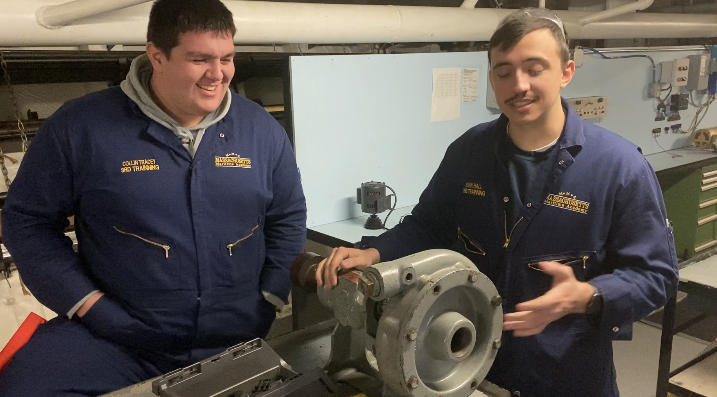 two cadets stand by pump on table