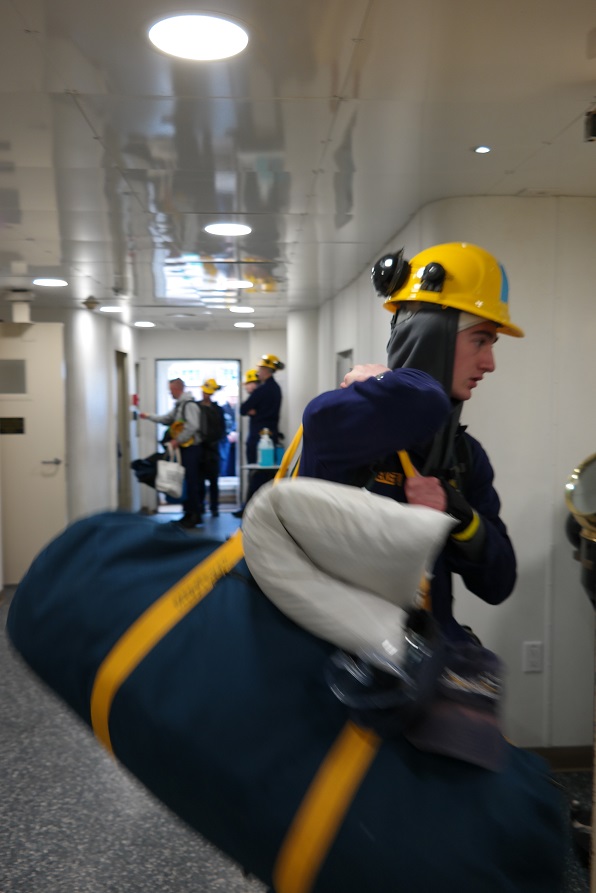 cadets carry sea bags onto ship