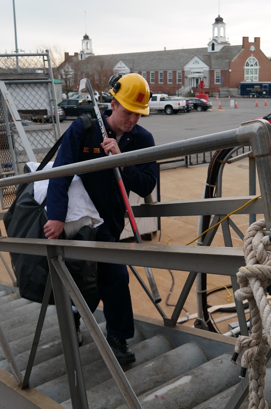 cadets carry sea bags onto ship