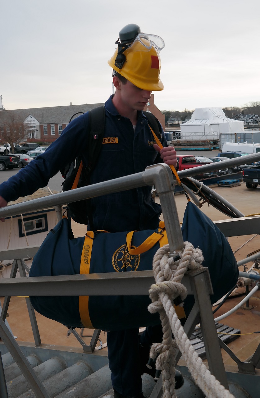 cadets carry sea bags onto ship