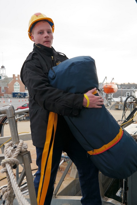 cadets carry sea bags onto ship