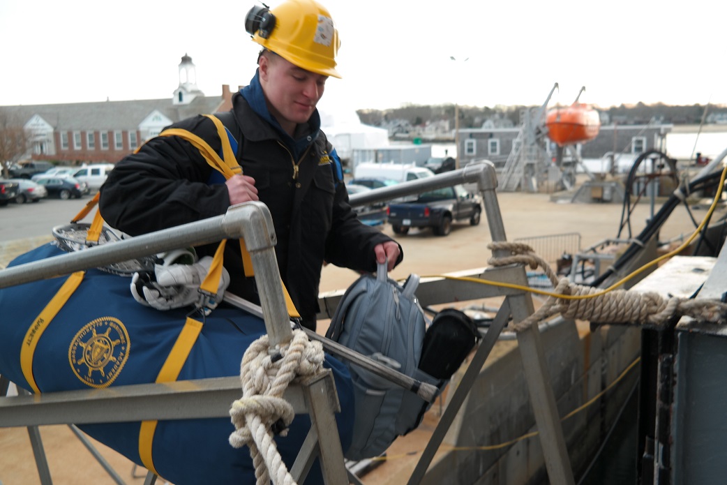 cadets carry sea bags onto ship