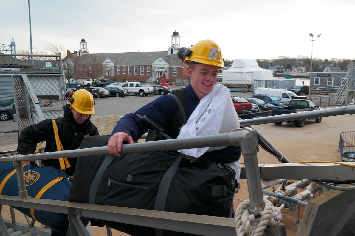 cadets carry sea bags onto ship