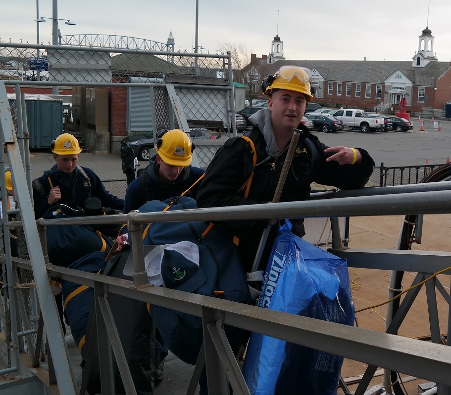 cadets carry sea bags onto ship