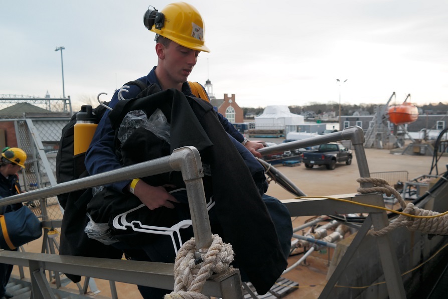 cadets carry sea bags onto ship