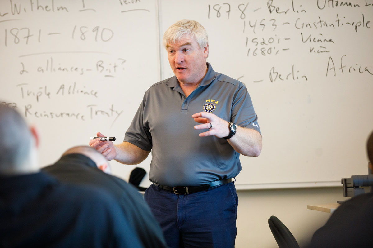 a social science professor teaching in front of a white board