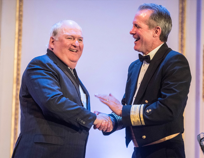 admiral shaking recipient of maritime person of the year