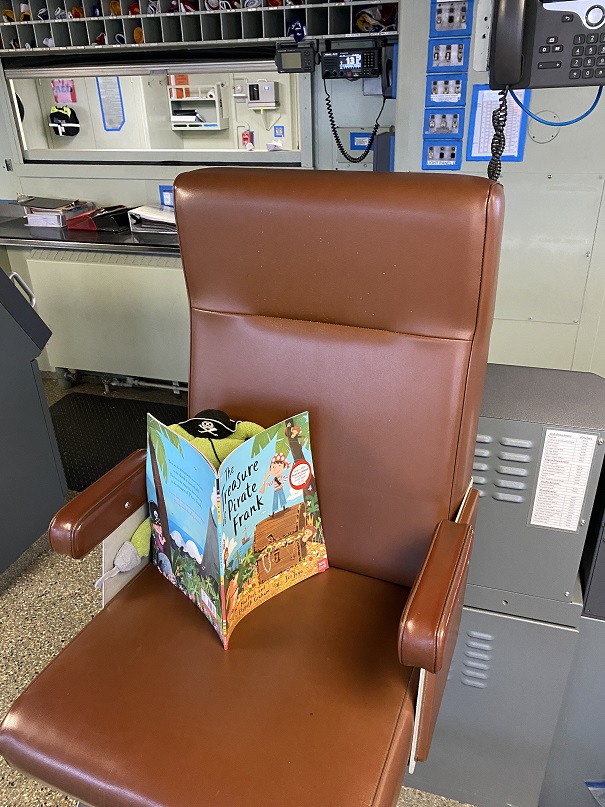 Little Buc reading book in Captain's chair