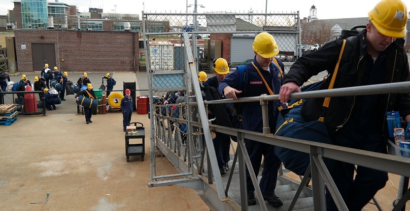 cadets carry sea bags onto ship