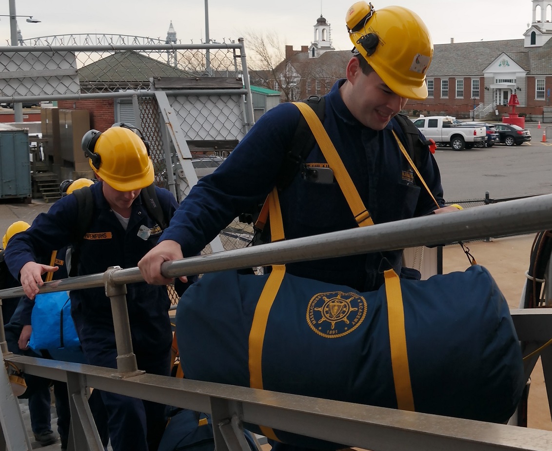 cadets carry sea bags onto ship