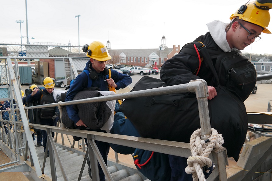 cadets carry sea bags onto ship