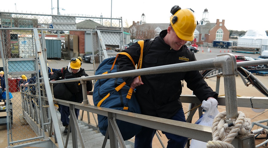 cadets carry sea bags onto ship