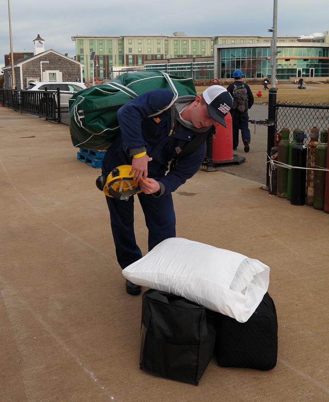 cadets carry sea bags onto ship