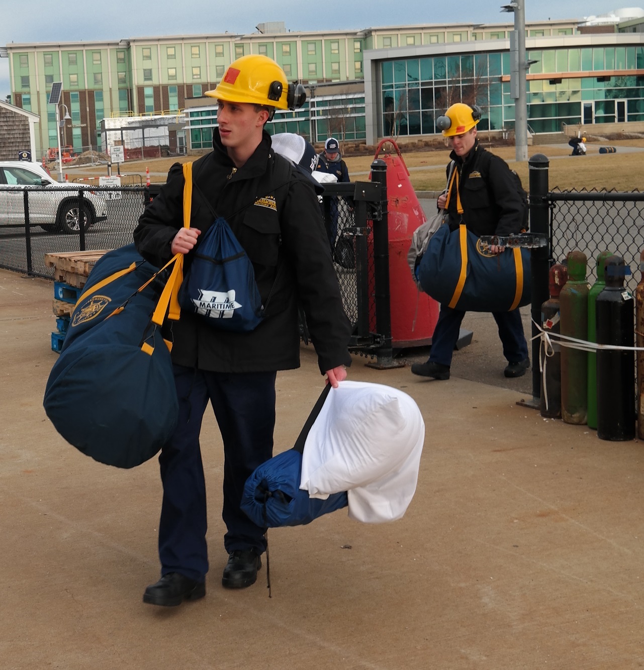 cadets carry sea bags onto ship