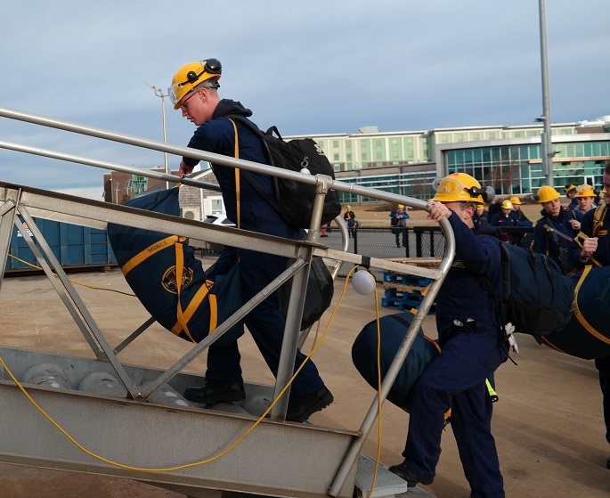 cadets carry sea bags onto ship