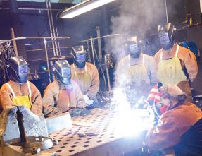 students and instructor in a welding lab